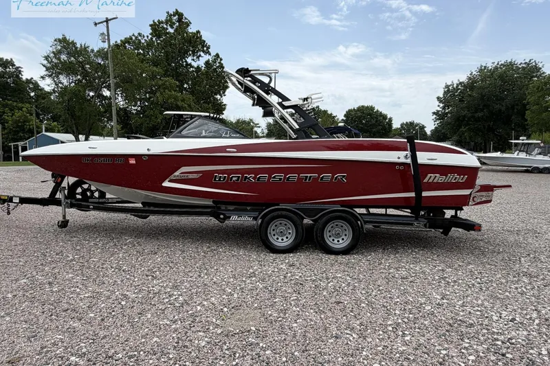 The Image of 2014 Malibu Wakesetter 24 MXZ boat on trailer, parked outdoors. - 1