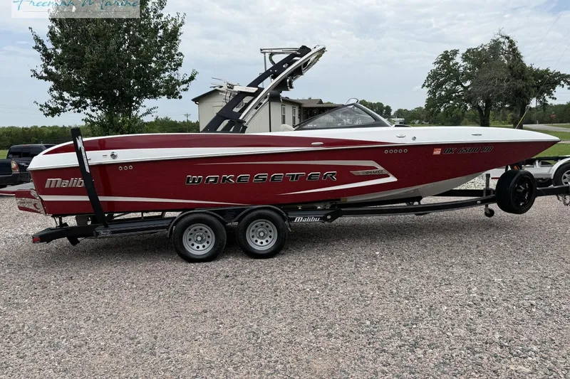 Slide: The Image of 2014 Malibu Wakesetter 24 MXZ boat on trailer, red and white design, parked outdoors. - 7