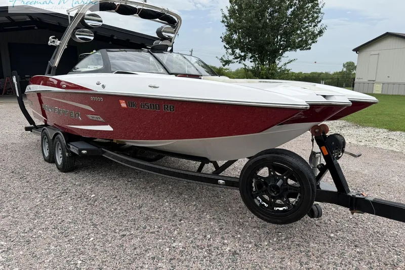 Slide: The Image of 2014 Malibu Wakesetter 24 MXZ boat on trailer, red and white design, parked outdoors. - 8