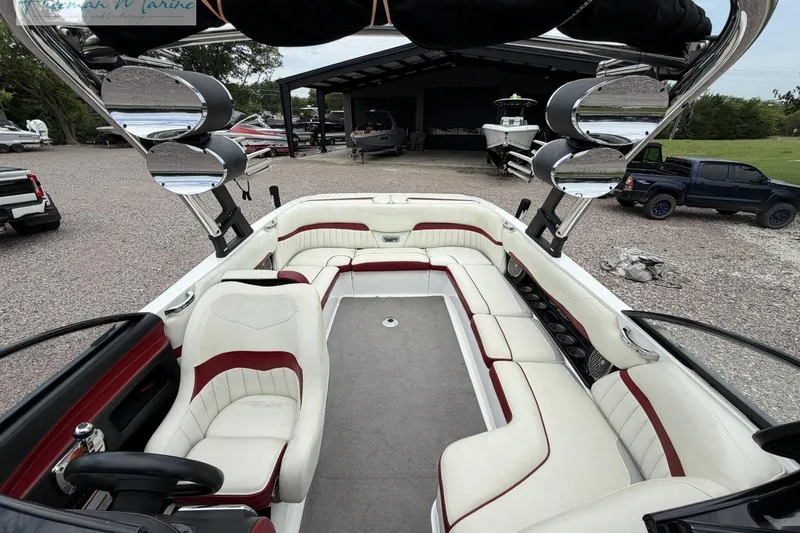 Slide: The Image of 2014 Malibu Wakesetter 24 MXZ boat interior with white and red seating, parked outdoors. - 12