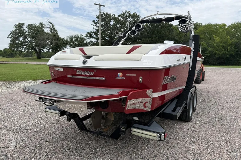 Slide: The Image of 2014 Malibu Wakesetter 24 MXZ boat on trailer, red and white design, parked outdoors. - 6