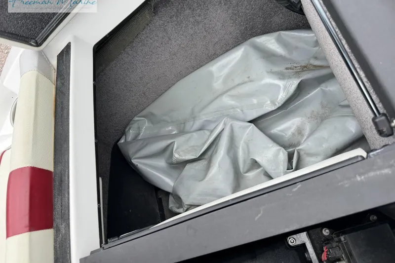 Slide: The Image of Storage compartment of a 2014 Malibu Wakesetter 24 MXZ boat with gray cover inside. - 28