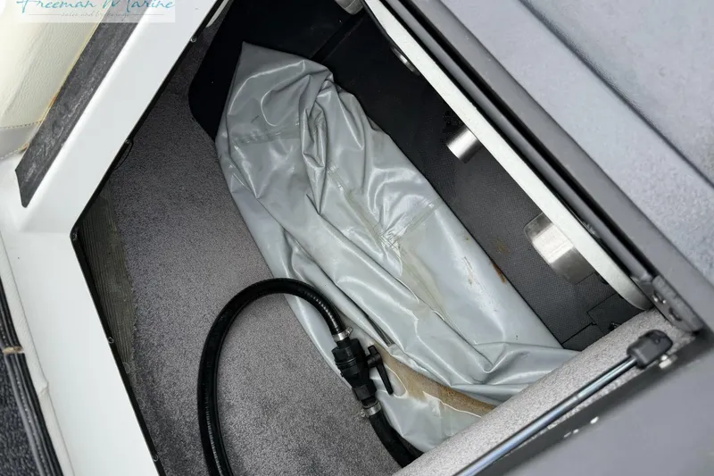 Slide: The Image of Storage compartment in a 2014 Malibu Wakesetter 24 MXZ boat, featuring a hose and cover. - 29