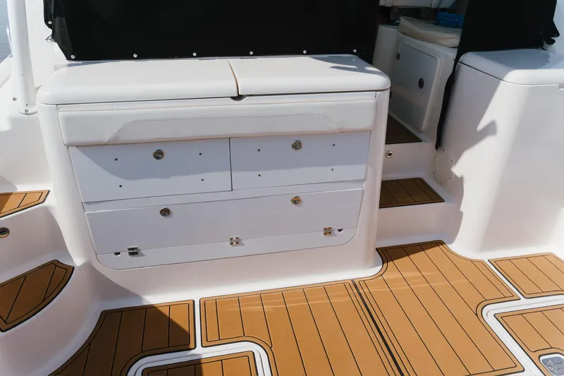 Slide: The Image of 2013 Pursuit OS 345 Offshore boat interior with white storage drawers and teak flooring. - 17