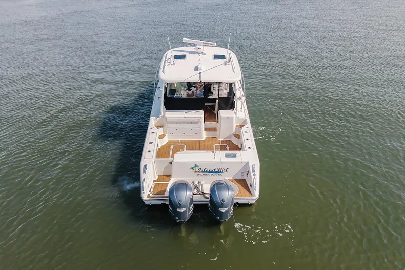 Slide: The Image of 2013 Pursuit OS 345 Offshore boat cruising on calm water, rear view. - 4