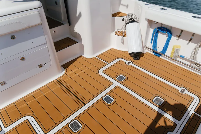 Slide: The Image of 2013 Pursuit OS 345 Offshore boat deck with teak flooring and storage compartments. - 12