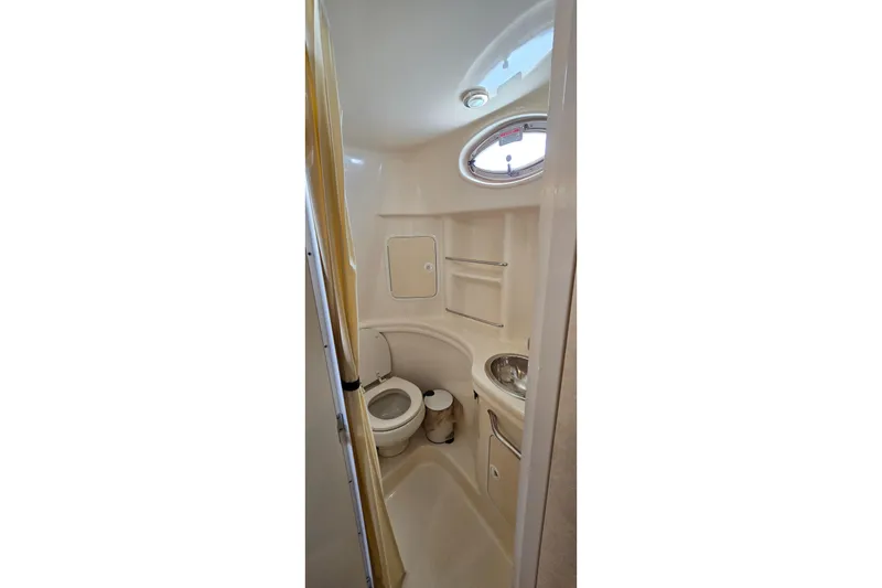 Slide: The Image of Compact bathroom in 2002 Sea Ray 300 Sundancer boat with toilet, sink, and porthole window. - 24