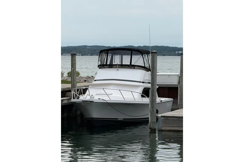 Slide: The Image of 1999 Blackfin 33 Flybridge boat docked at a marina with scenic water backdrop. - 10