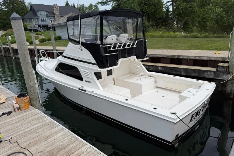 Slide: The Image of 1999 Blackfin 33 Flybridge boat docked at a marina, surrounded by greenery. - 5