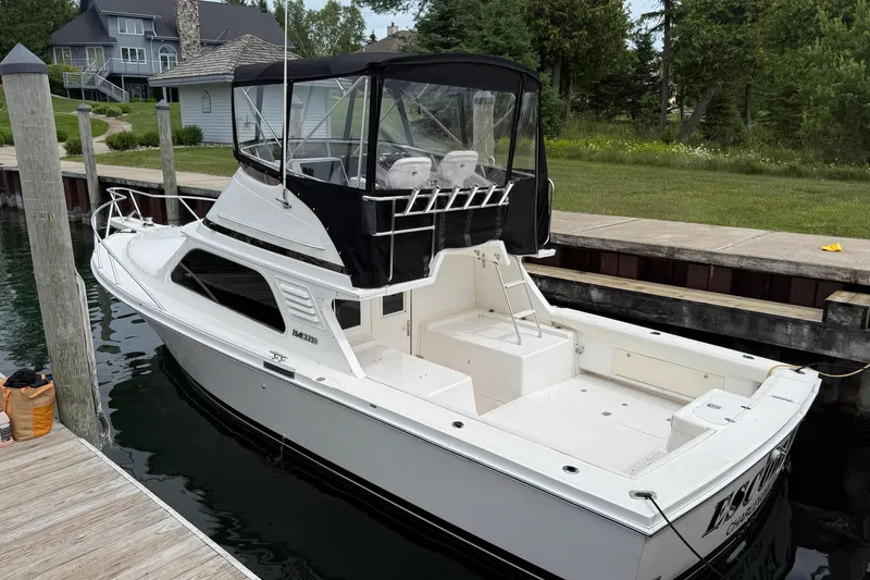 Slide: The Image of 1999 Blackfin 33 Flybridge boat docked, featuring a spacious deck and flybridge enclosure. - 2