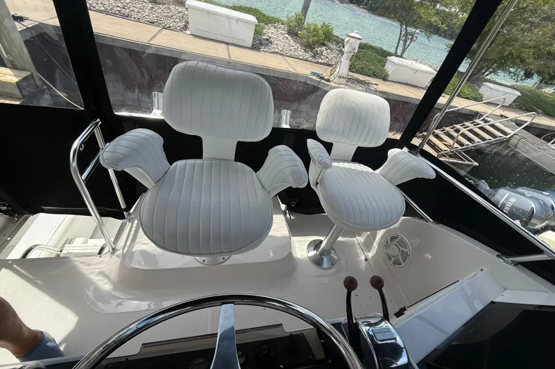 Slide: The Image of Flybridge of 1999 Blackfin 33 with white captain chairs and steering wheel. - 27