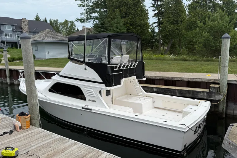 Slide: The Image of 1999 Blackfin 33 Flybridge boat docked, featuring a sleek white design and spacious deck. - 4