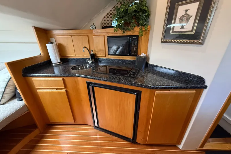 Slide: The Image of Compact kitchen area in a 1999 Blackfin 33 Flybridge boat with wood cabinetry and modern appliances. - 40