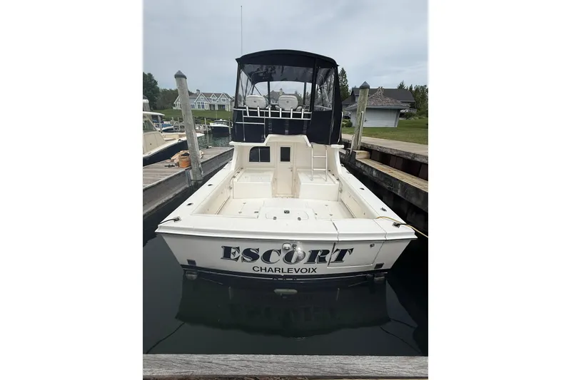 Slide: The Image of 1999 Blackfin 33 Flybridge boat docked, rear view with "ESCORT" and "CHARLEVOIX" text. - 12