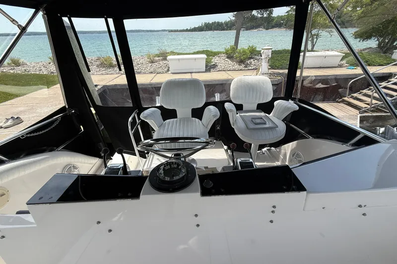 Slide: The Image of 1999 Blackfin 33 Flybridge interior with white captain chairs and scenic waterfront view. - 26