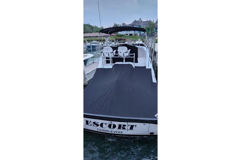 Slide: The Image of 1999 Blackfin 33 Flybridge boat docked, covered, with "Escort" and "Charlevoix" on the stern. - 11