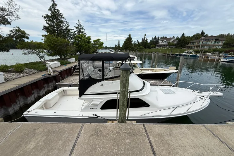 Slide: The Image of 1999 Blackfin 33 Flybridge boat docked in a scenic marina setting. - 6