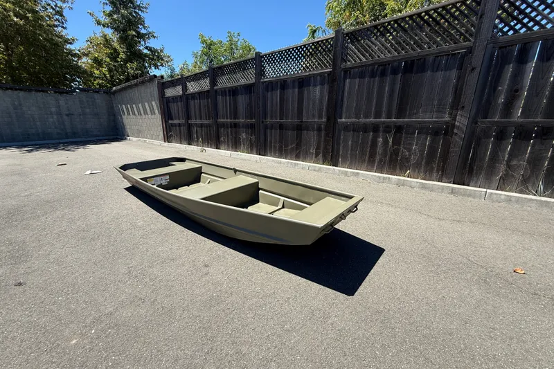 Slide: The Image of 2026 Tracker Grizzly 14 Jon boat on pavement, near wooden fence, under clear blue sky. - 7