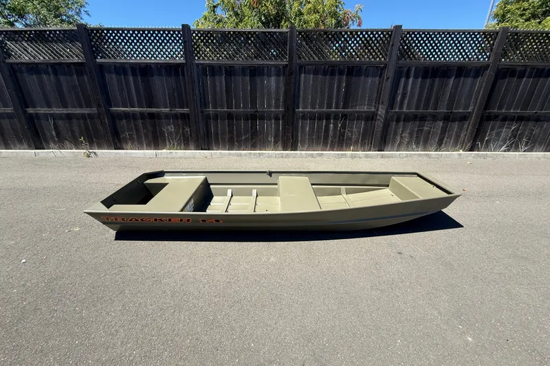 Slide: The Image of 2026 Tracker Grizzly 14 Jon boat on pavement, black fence background. - 5