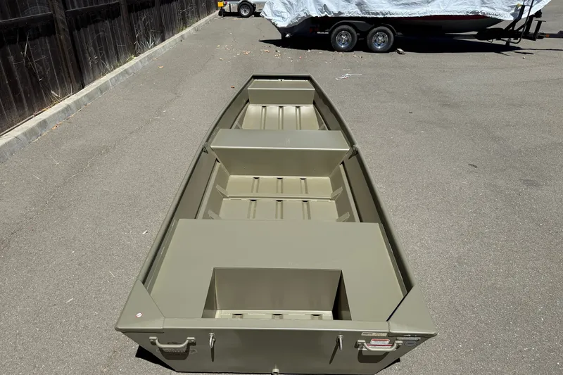 Slide: The Image of 2026 Tracker Grizzly 14 Jon boat on pavement, with trailer in background. - 6