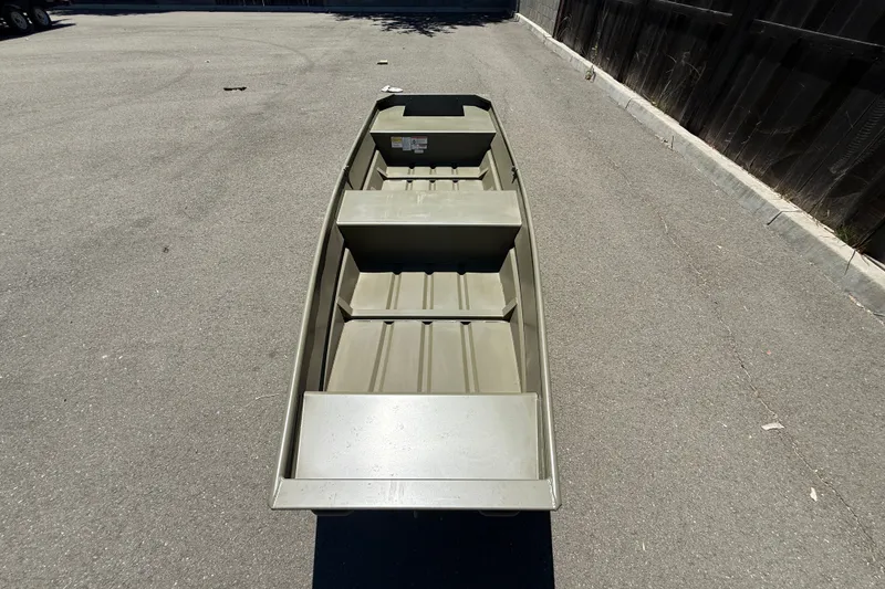 Slide: The Image of 2026 Tracker Grizzly 14 Jon boat on pavement, showcasing interior seating and design. - 3