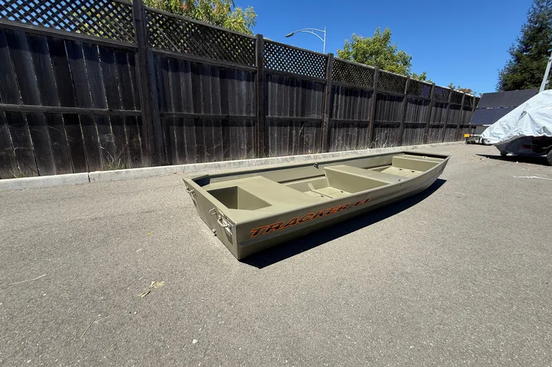 Slide: The Image of 2026 Tracker Grizzly 14 Jon boat on pavement, wooden fence background. - 4