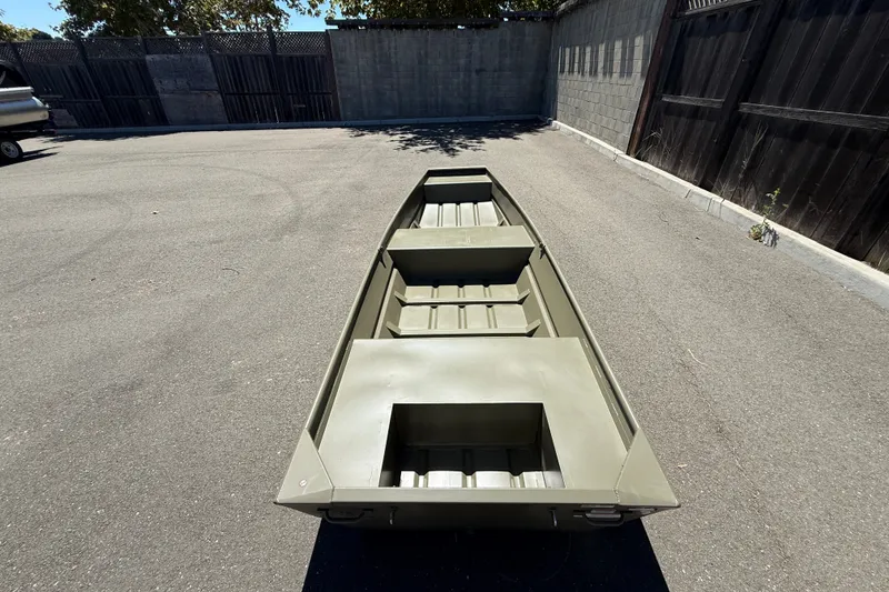 Slide: The Image of 2026 Tracker Grizzly 14 Jon boat in a paved outdoor area, showcasing its interior layout. - 2
