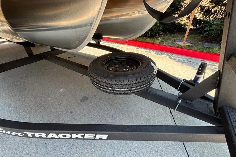 Slide: The Image of 2026 Sun Tracker Party Barge 22 XP3 trailer with spare tire on concrete surface. - 50