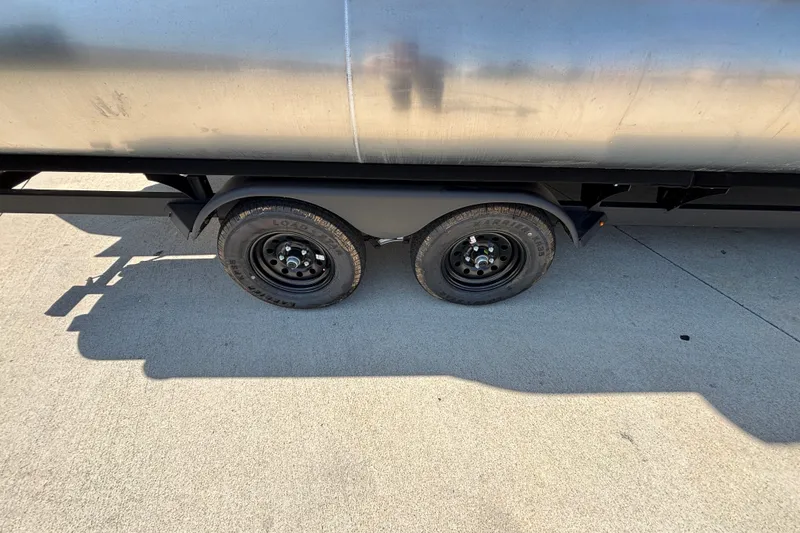 Slide: The Image of Trailer wheels of a 2026 Sun Tracker Party Barge 22 XP3 on concrete surface. - 53