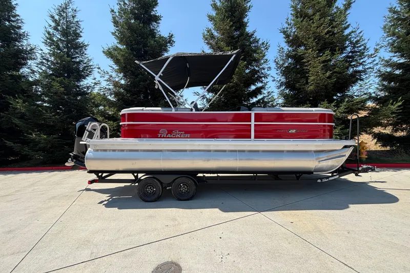 The Image of 2026 Sun Tracker Party Barge 22 XP3 pontoon boat on trailer, parked outdoors. - 0