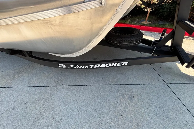 Slide: The Image of 2026 Sun Tracker Party Barge 22 XP3 trailer with logo, parked on concrete. - 52
