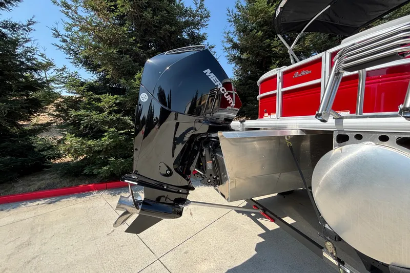 Slide: The Image of 2026 Sun Tracker Party Barge 22 XP3 with Mercury outboard motor, parked near trees. - 46