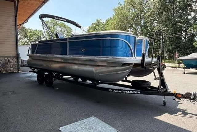 Slide: The Image of 2026 Sun Tracker Party Barge 22 RF DLX pontoon boat on trailer, parked outdoors. - 1