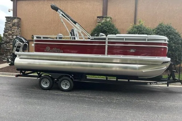 The Image of 2026 Sun Tracker SportFish 20 DLX pontoon boat on trailer, parked outdoors. - 0
