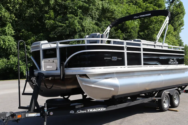 Slide: The Image of 2026 Sun Tracker SportFish 20 DLX pontoon boat on trailer, parked near lush greenery. - 4