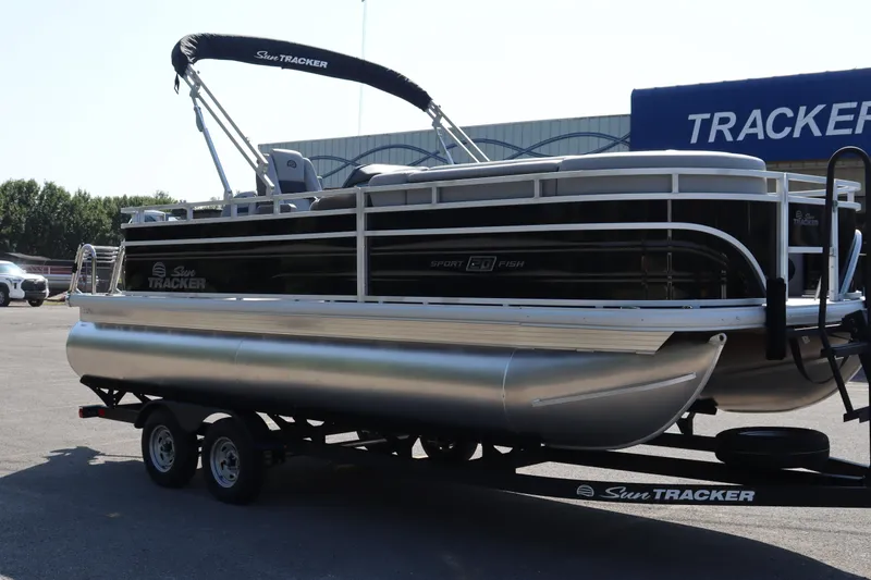 Slide: The Image of 2026 Sun Tracker SportFish 20 DLX pontoon boat on trailer, parked outdoors. - 2