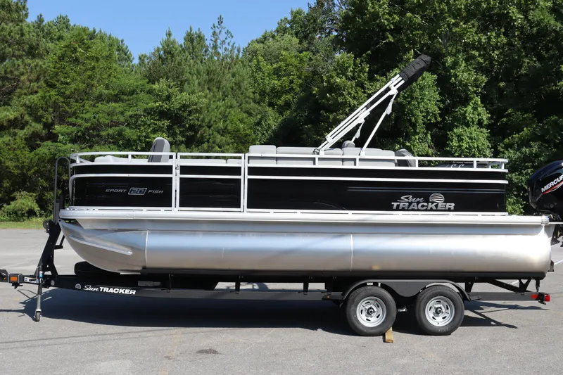 Slide: The Image of 2026 Sun Tracker SportFish 20 DLX pontoon boat on trailer, surrounded by lush greenery. - 5