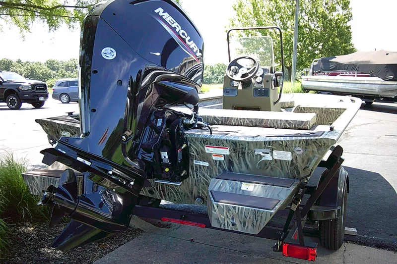 Slide: The Image of 2026 Tracker Grizzly 1860 CC boat with Mercury outboard motor, parked outdoors. - 2