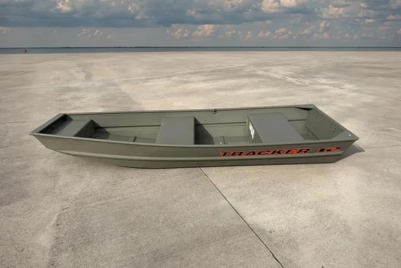 The Image of 2026 Tracker Grizzly 12 Jon boat on concrete surface under cloudy sky. - 0
