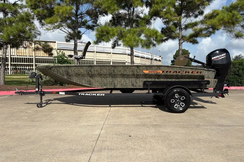 The Image of 2026 Tracker Grizzly 1756 T Marsh boat on trailer, outdoors with trees in background. - 0