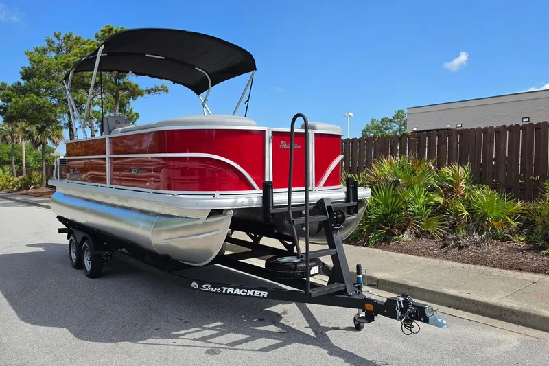 Slide: The Image of 2026 Sun Tracker Party Barge 20 DLX pontoon boat on trailer, red exterior, parked outdoors. - 5