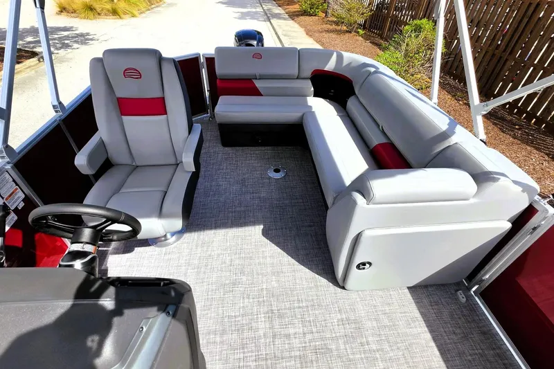 Slide: The Image of 2026 Sun Tracker Party Barge 20 DLX interior with gray and red seating, steering wheel, and carpeted floor. - 13