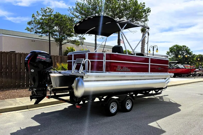 Slide: The Image of 2026 Sun Tracker Party Barge 20 DLX pontoon boat on trailer, parked outdoors. - 2