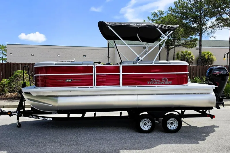 Slide: The Image of 2026 Sun Tracker Party Barge 20 DLX pontoon boat on trailer, red and silver design. - 7