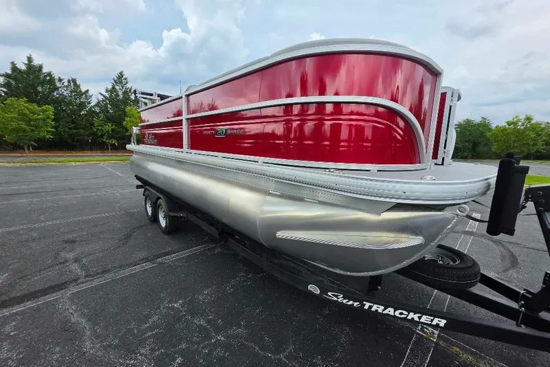 The Image of 2026 Sun Tracker Party Barge 20 DLX pontoon boat on trailer, parked outdoors. - 0