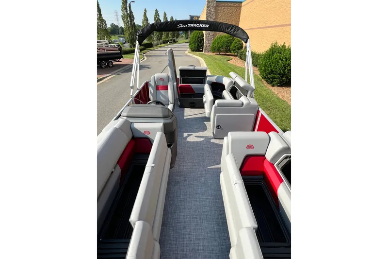 Slide: The Image of 2026 Sun Tracker Party Barge 20 DLX interior with gray and red seating, outdoor setting. - 9