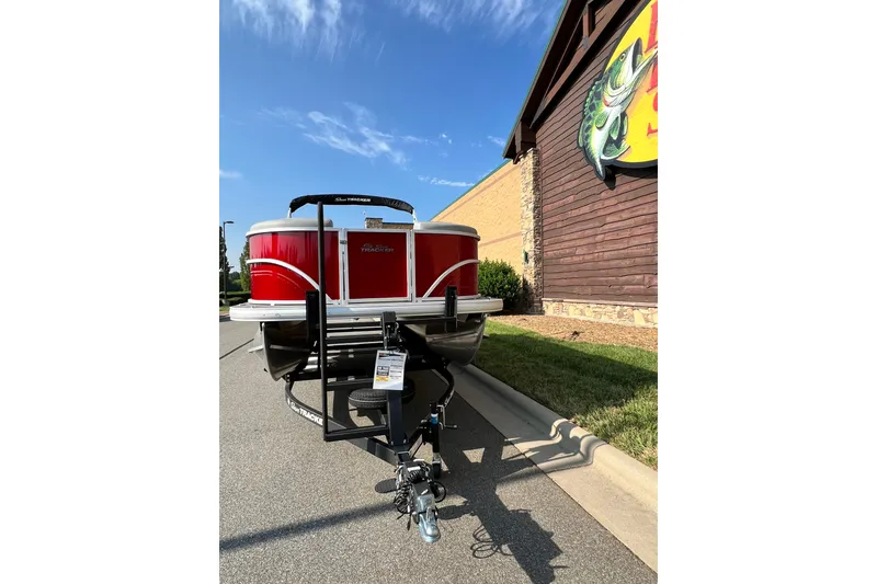 Slide: The Image of 2026 Sun Tracker Party Barge 20 DLX pontoon boat on trailer, parked outside a store. - 6