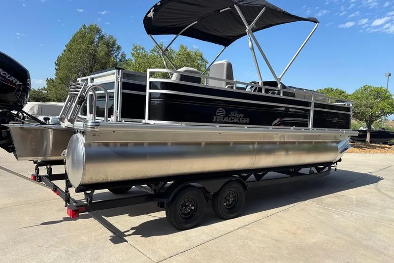 Slide: The Image of 2026 Sun Tracker Fishin' Barge 22 DLX pontoon boat on trailer, outdoors. - 11