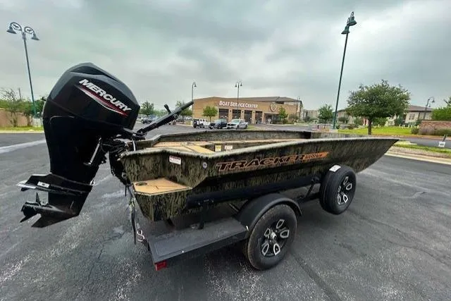 Slide: The Image of 2026 Tracker Grizzly 1756 T Marsh boat on trailer, parked outdoors near a boat shop. - 3