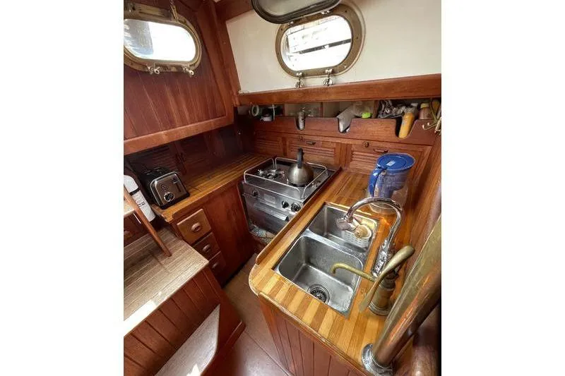 Slide: The Image of Compact galley kitchen in 1980 Ta Shing Baba 30 sailboat with wooden cabinetry and stainless steel sink. - 9